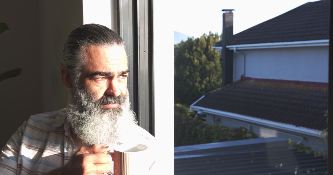 Senior Man with Long Beard Relaxing by the Window