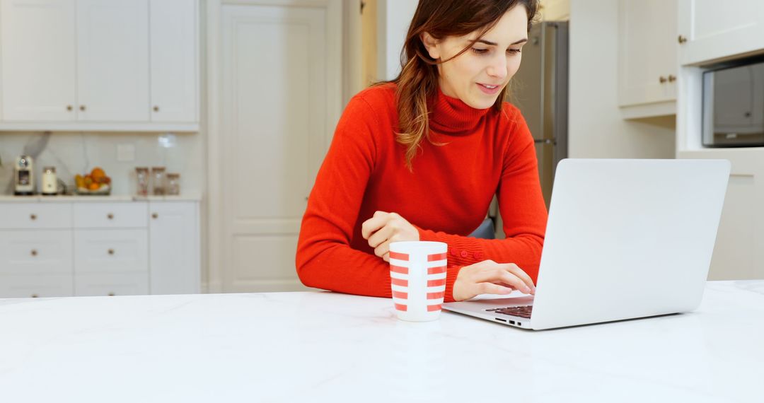 Young Woman Working on Laptop in Modern Kitchen with Coffee Mug - Free Images, Stock Photos and Pictures on Pikwizard.com