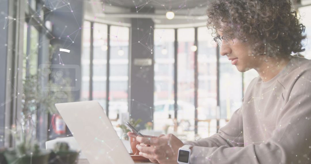 Young Man Using Smartphone in Modern Cafe Workspace