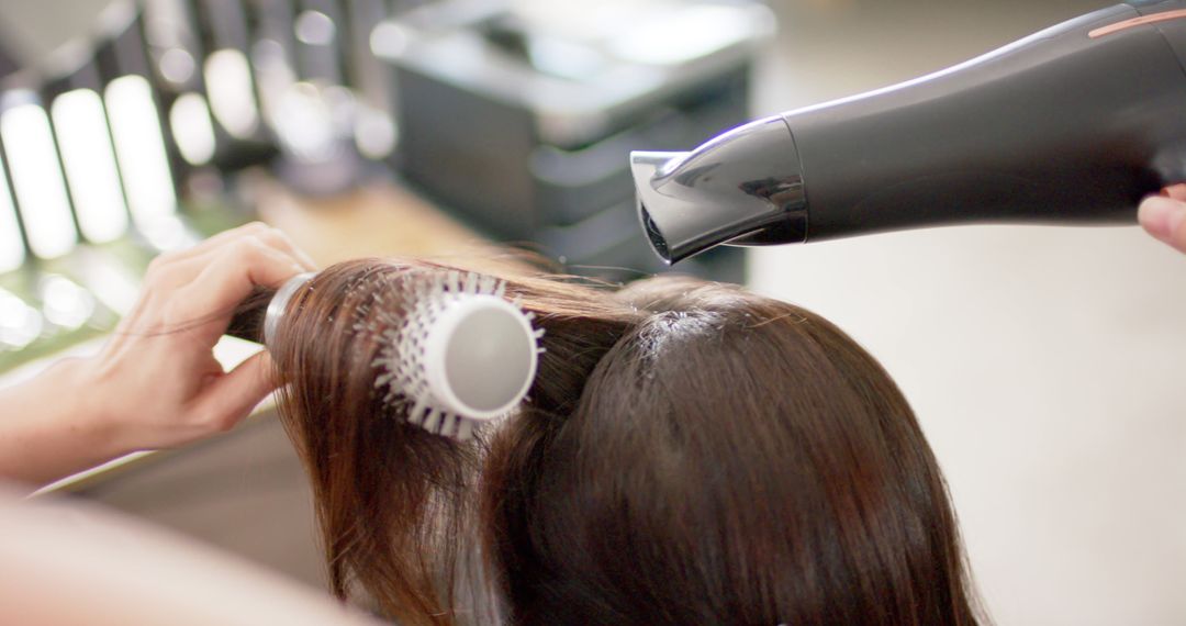 Stylist Using Hair Dryer and Round Brush in Salon - Free Images, Stock Photos and Pictures on Pikwizard.com