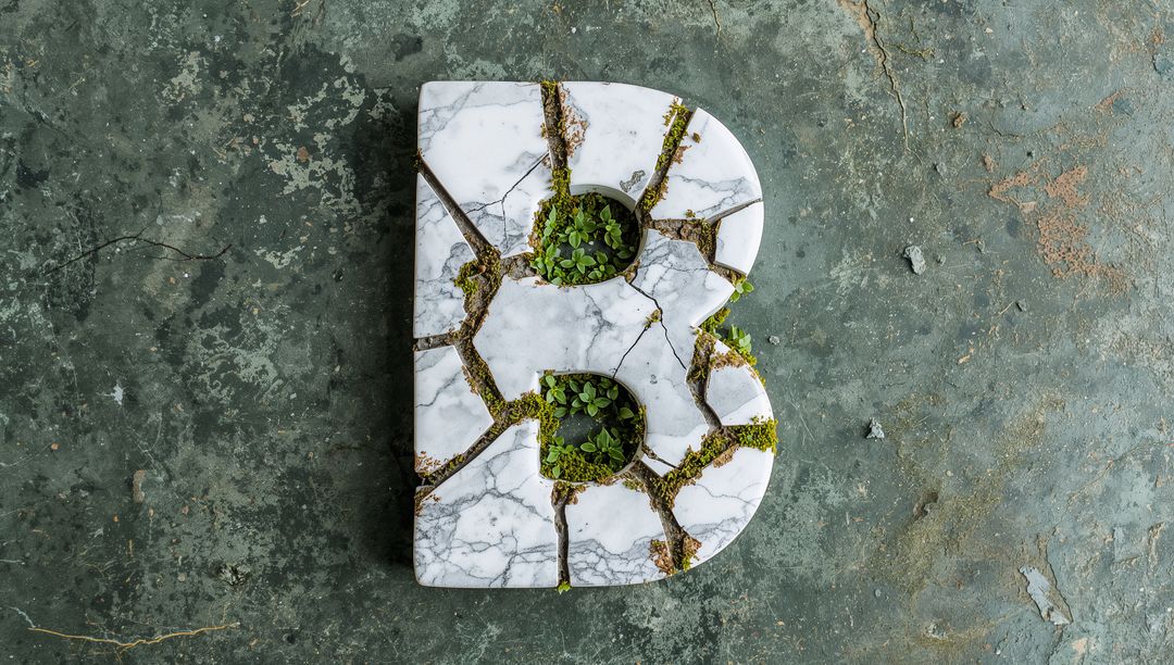Marble Letter B with Moss on Textured Concrete