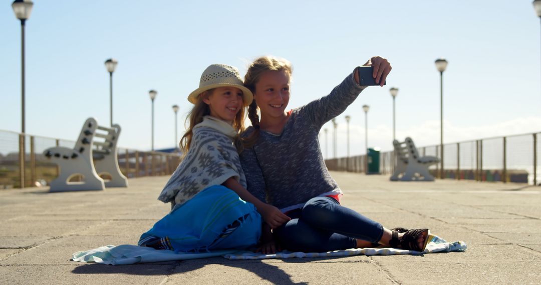 Two Girls Taking a Selfie on a Sunny Boardwalk - Free Images, Stock Photos and Pictures on Pikwizard.com