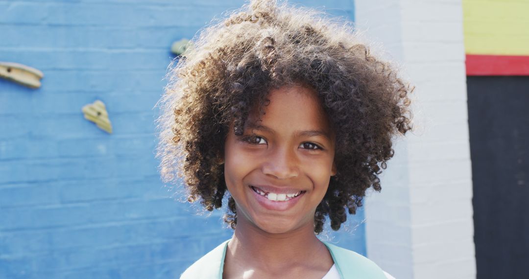 Smiling Child with Curly Hair Standing Outdoors - Free Images, Stock Photos and Pictures on Pikwizard.com