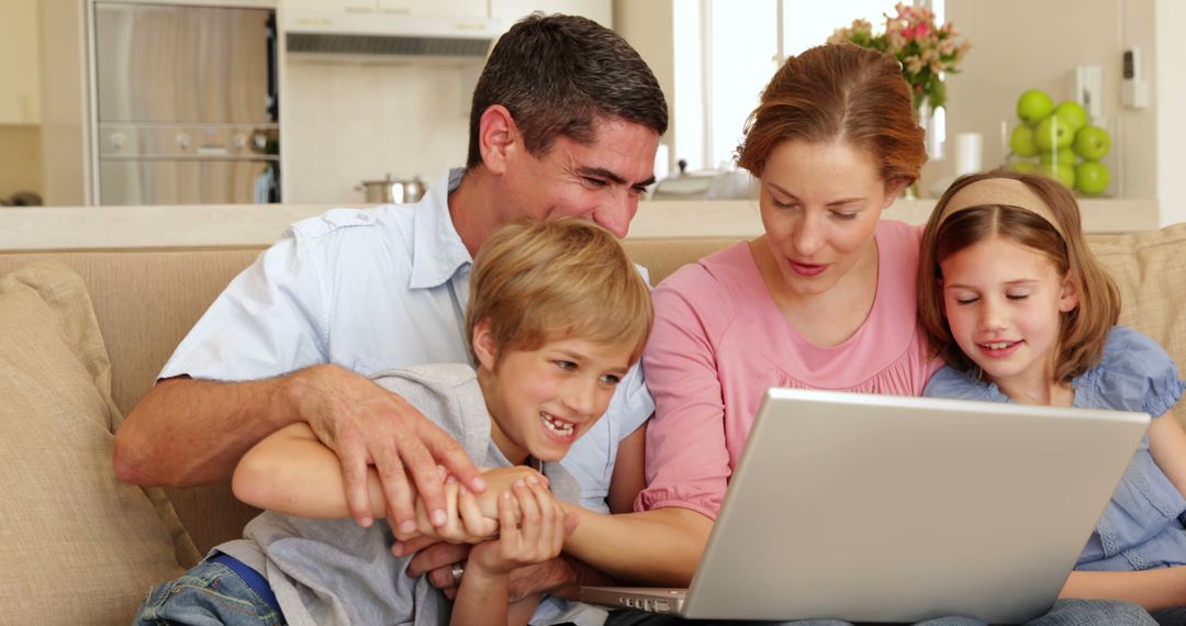 Happy Family of Four Using Laptop on Couch - Free Images, Stock Photos and Pictures on Pikwizard.com