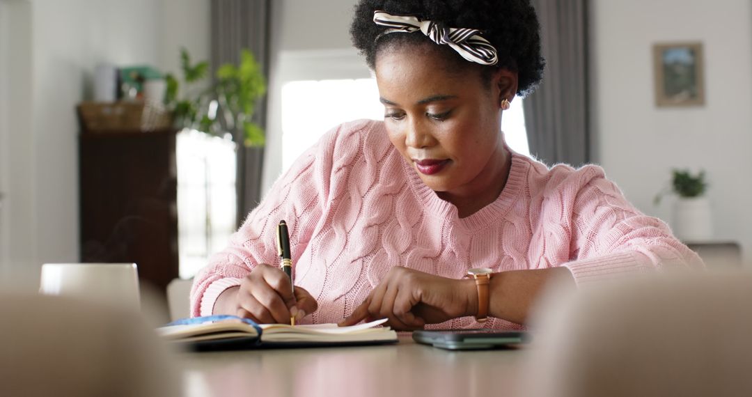 Focused Woman Writing in a Notebook at Home