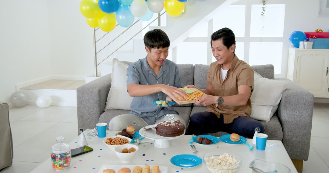 Father and Son Celebrating Birthday with Cake and Snacks at Home