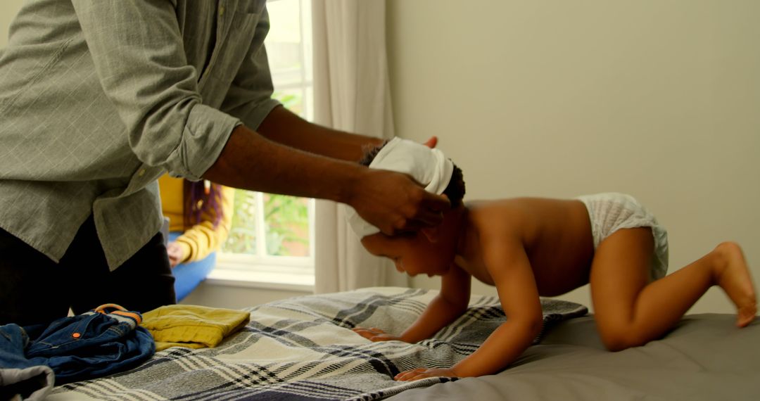 Father Dressing Baby on Bed in Cozy Bedroom - Free Images, Stock Photos and Pictures on Pikwizard.com