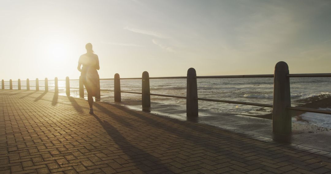 Silhouette of Person Running Along the Ocean at Sunset - Free Images, Stock Photos and Pictures on Pikwizard.com