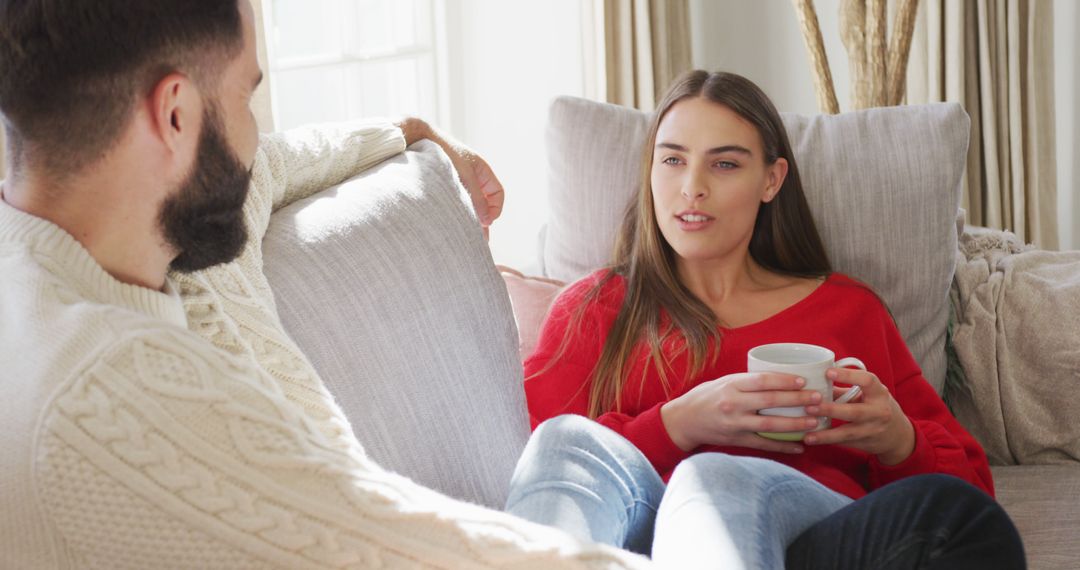 Image of happy caucasian couple siting on sofa and drinking coffee - Free Images, Stock Photos and Pictures on Pikwizard.com