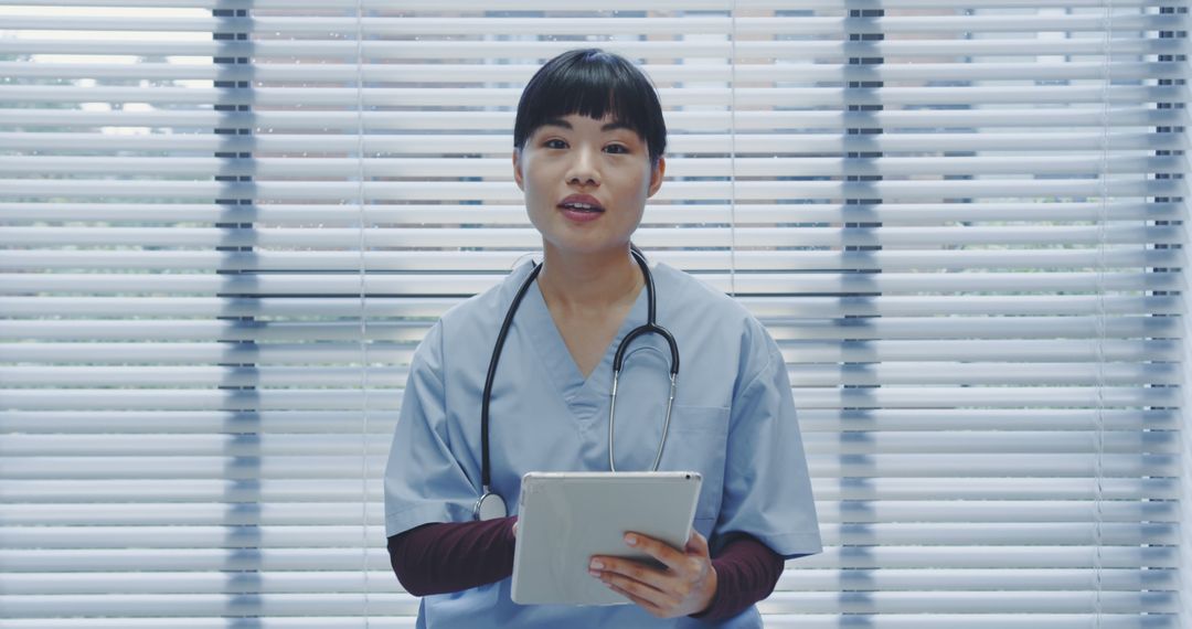 Smiling Nurse Holding Digital Tablet in Bright Clinic - Free Images, Stock Photos and Pictures on Pikwizard.com