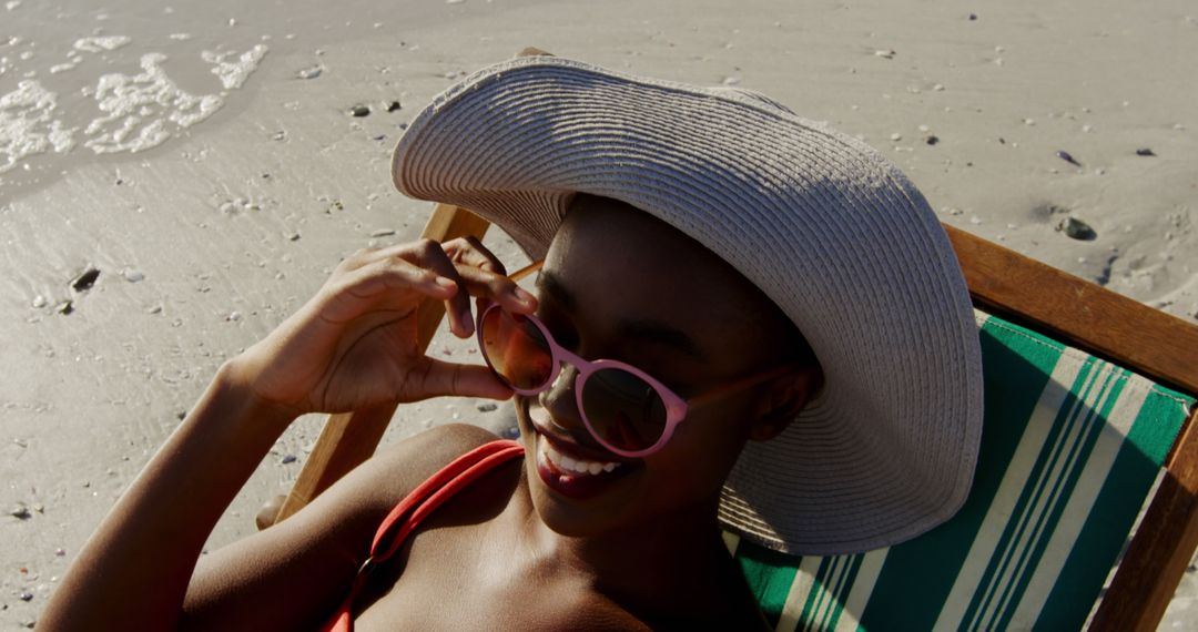 Young Woman Relaxing on Beach with Sun Hat and Sunglasses - Free Images, Stock Photos and Pictures on Pikwizard.com