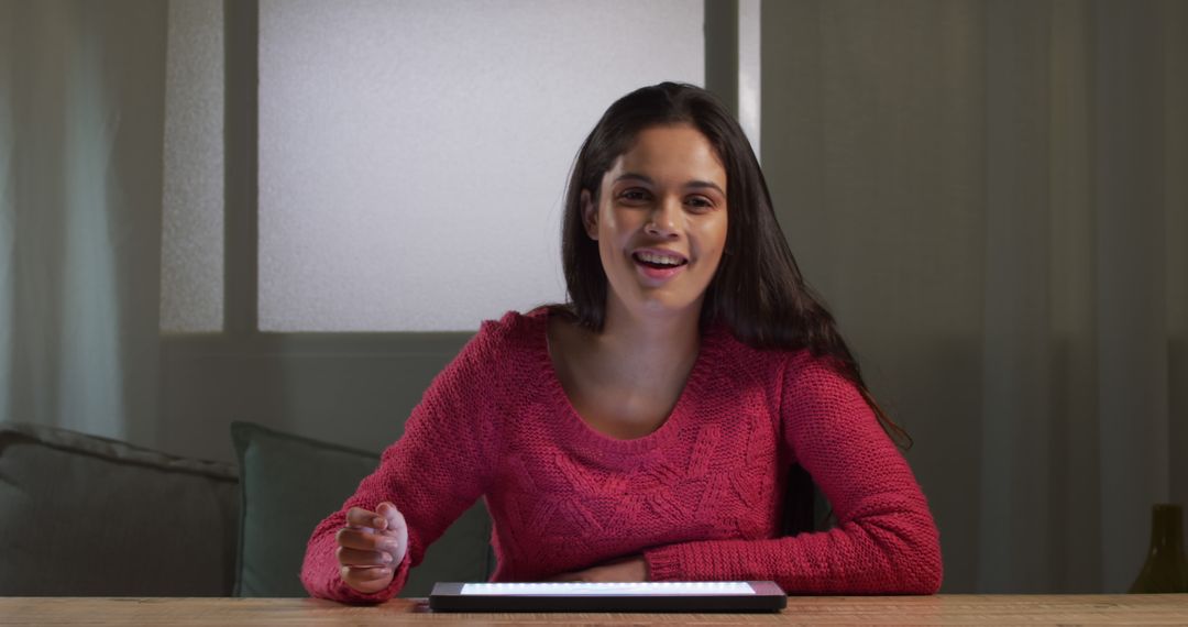 Young woman smiling sitting at desk using tablet during nighttime indoors - Free Images, Stock Photos and Pictures on Pikwizard.com