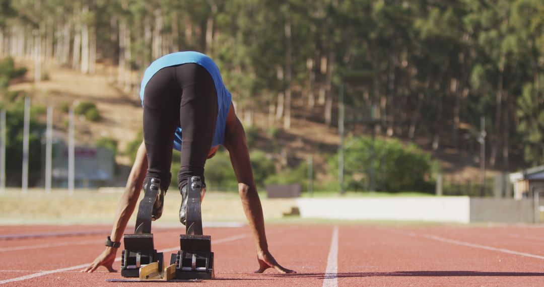 Athlete with Prosthetic Legs Preparing for Sprint on Track
