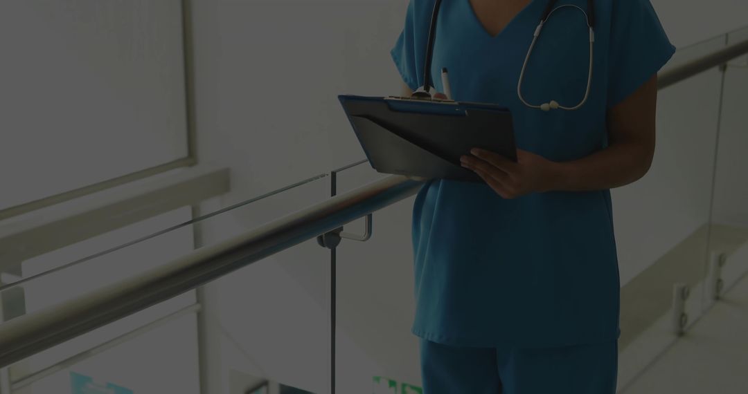 Nurse checking clipboard on hospital mezzanine with stethoscope and daylight
