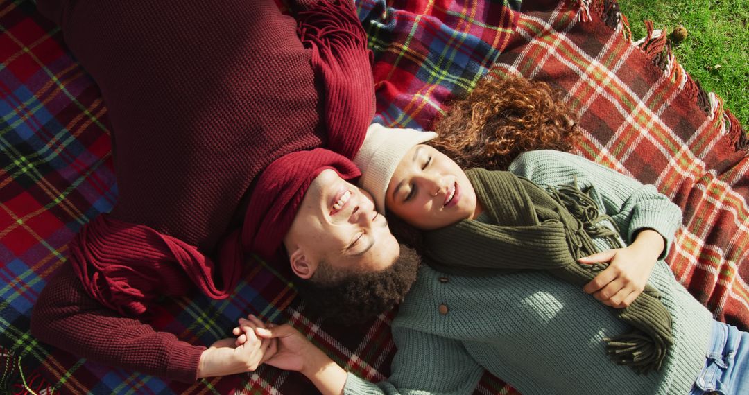 Image of biracial couple warmly dressed lying on blanket spending time in the garden - Free Images, Stock Photos and Pictures on Pikwizard.com