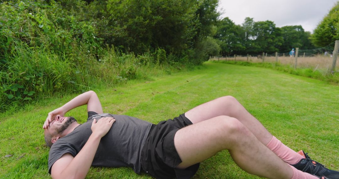 Man Relaxing on Grass After Jogging in Tranquil Park