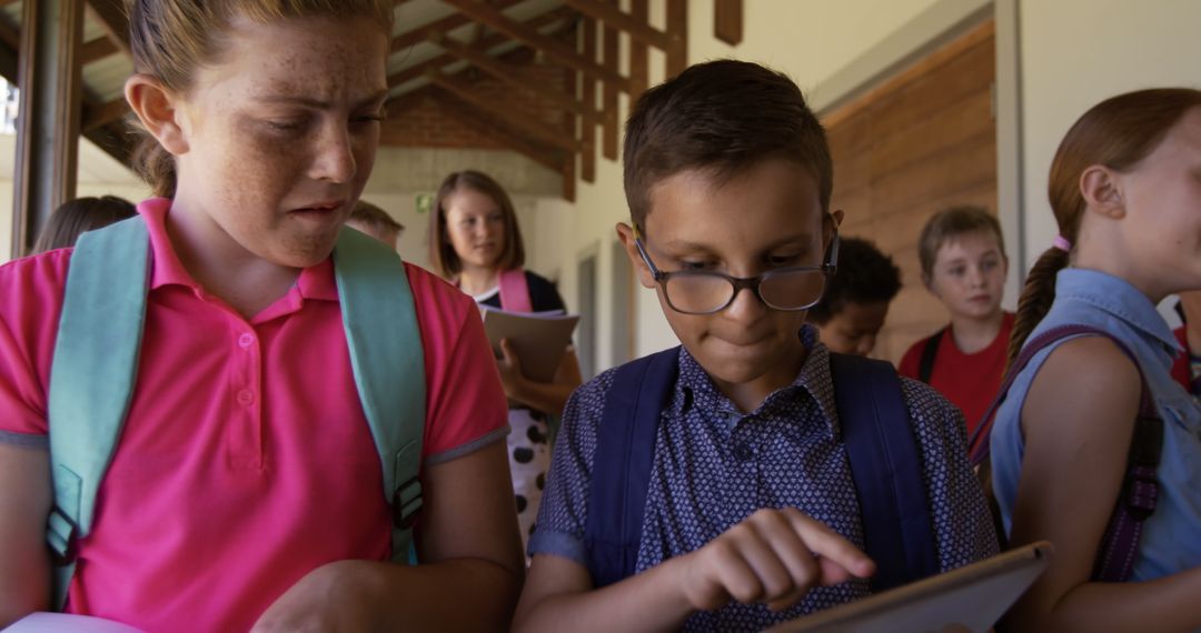 Schoolchildren Engaged with Tablet in Busy Corridor