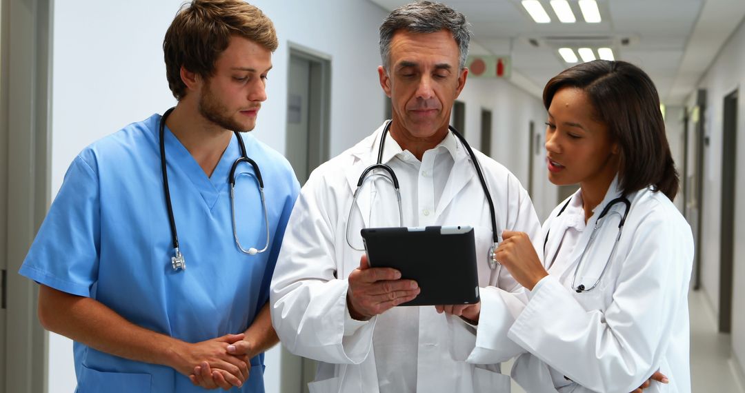 Diverse Medical Team Analyzing Data on Digital Tablet in Hospital Corridor