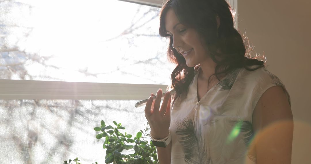 Woman Smiling While Talking on Smartphone by Sunny Window