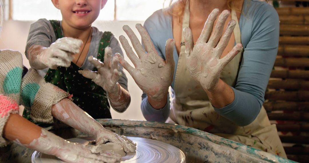 Smiling Woman and Child Learning Pottery Together with Muddy Hands - Free Images, Stock Photos and Pictures on Pikwizard.com