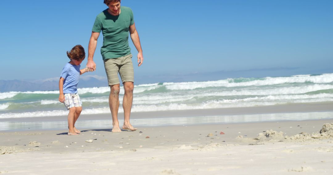 Father and Son Walking on Sandy Beach Holding Hands - Free Images, Stock Photos and Pictures on Pikwizard.com