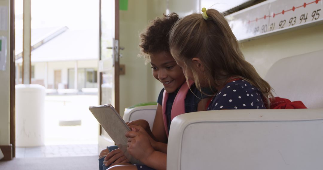 Joyful Girls Using Tablet Together in Classroom Setting