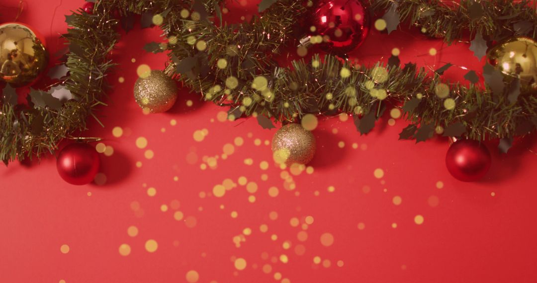 Golden Christmas Baubles and Garland on Red Background with Falling Glitter