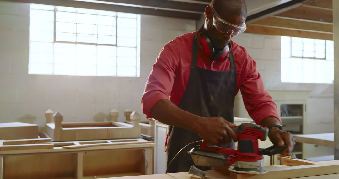 Carpenter Sanding Wooden Board with Electric Sander in Workshop