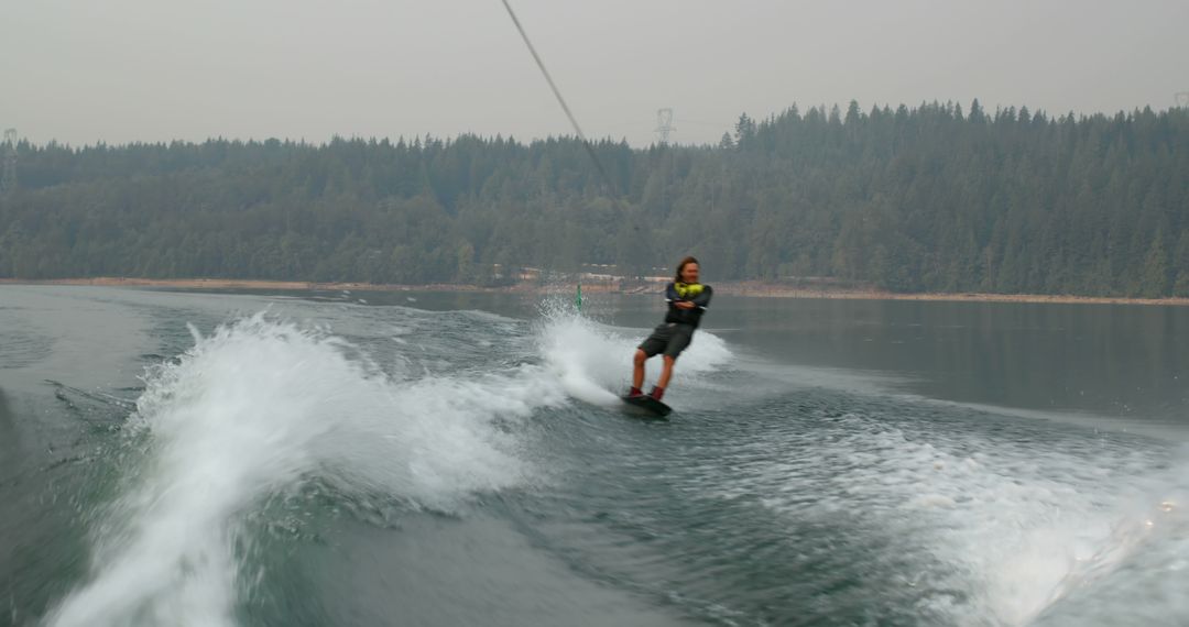 Man Wakeboarding on Lake with Forest in Background - Free Images, Stock Photos and Pictures on Pikwizard.com