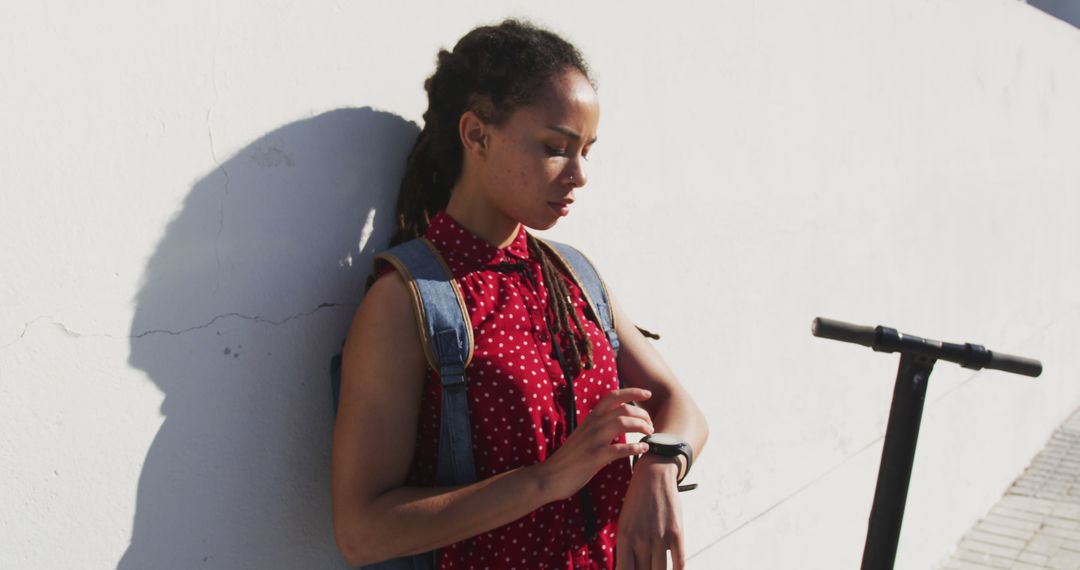 Young Woman with Dreadlocks Checking Smartwatch by Scooter - Free Images, Stock Photos and Pictures on Pikwizard.com