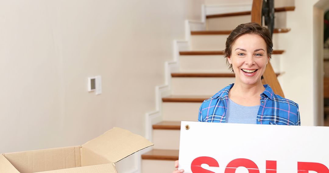 Smiling Woman Holding Sold Sign in New Home - Free Images, Stock Photos and Pictures on Pikwizard.com