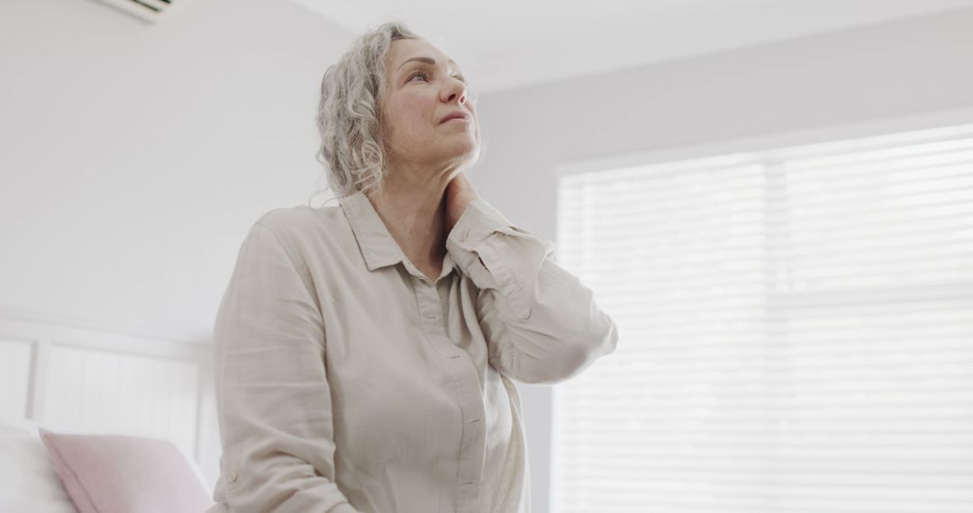 Senior Woman Touching Neck in Bedroom, Experiencing Pain - Free Images, Stock Photos and Pictures on Pikwizard.com