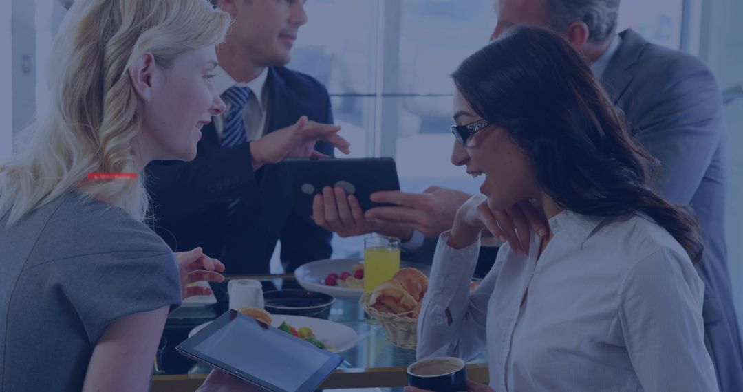 Business Team Collaborating Over Casual Breakfast Meeting With Tablets, Coffee, Pastries