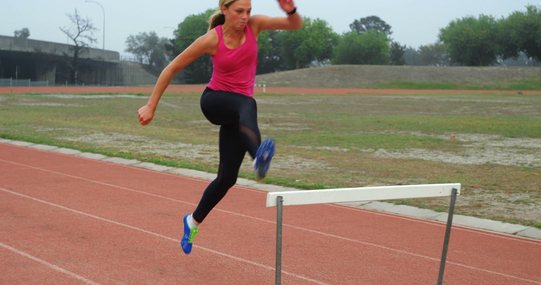 Female Athlete Jumping Over Hurdle During Training on Track - Free Images, Stock Photos and Pictures on Pikwizard.com