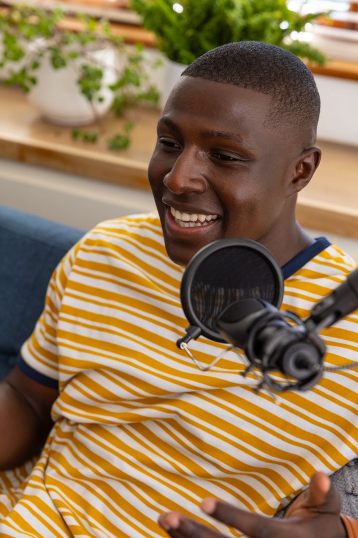 African American man recording podcast in home studio smiling and speaking into microphone