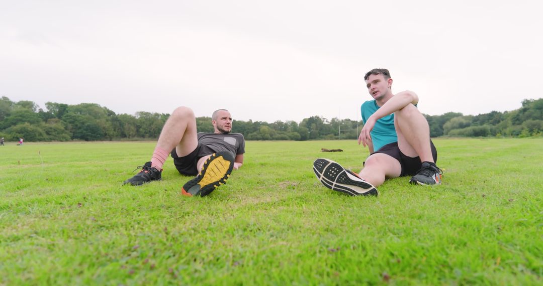 Men Relaxing on Grass After Jogging in Park