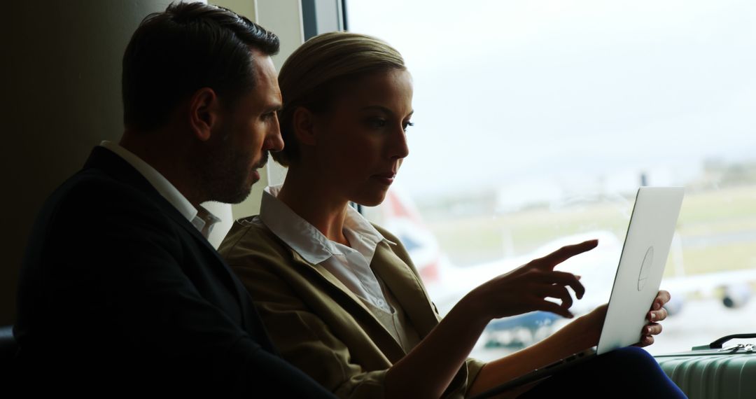 Professionals Collaborating on Laptop in Airport Lounge