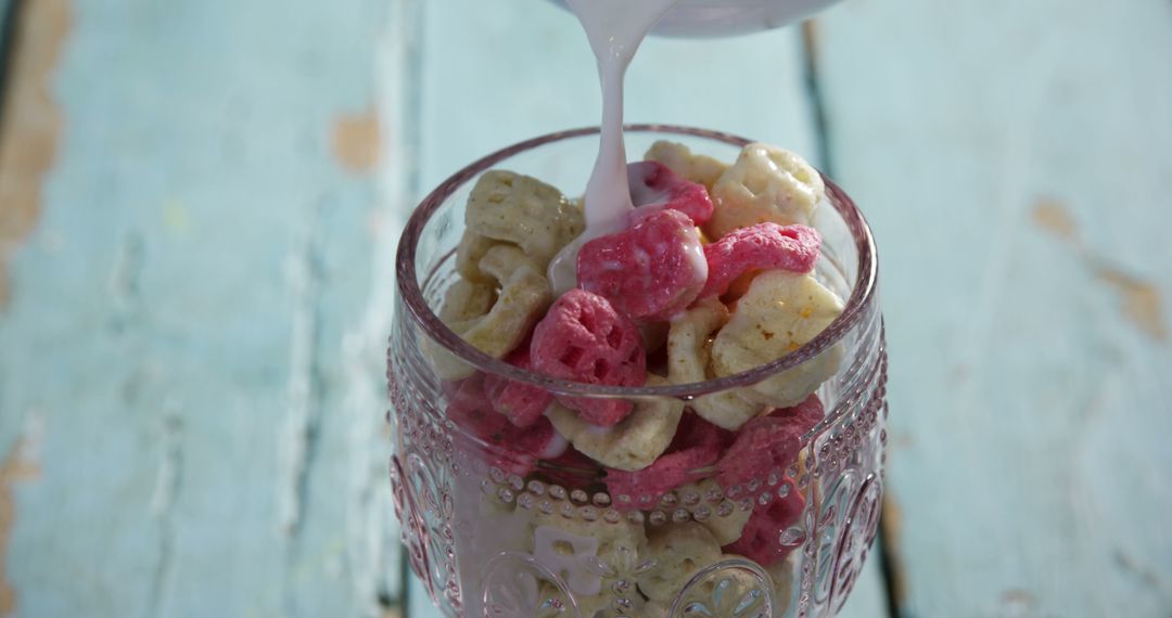 Pouring Milk Over Colorful Cereal in Glass Bowl on Wooden Table - Free Images, Stock Photos and Pictures on Pikwizard.com