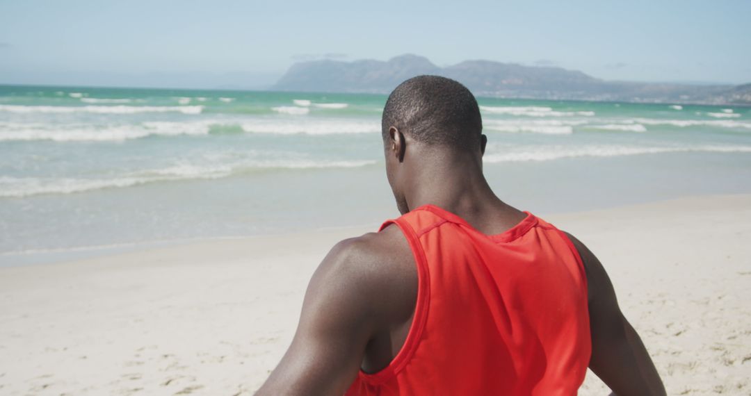 Athletic Man in Red Tank Top Facing Ocean on Sandy Beach - Free Images, Stock Photos and Pictures on Pikwizard.com