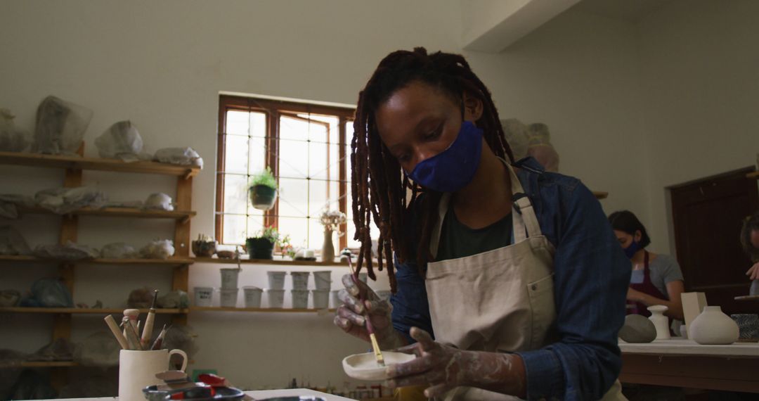 Artist with Dreadlocks Glazing Pottery in Artisan Workspace - Free Images, Stock Photos and Pictures on Pikwizard.com