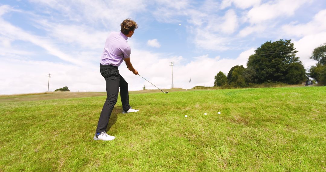 Man Playing Golf on Green Slope Under Blue Sky