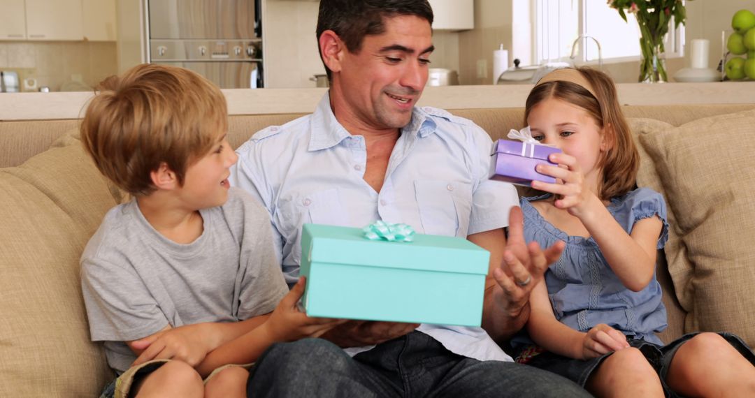 Father Enjoys Opening Gifts with Children on Couch at Home - Free Images, Stock Photos and Pictures on Pikwizard.com