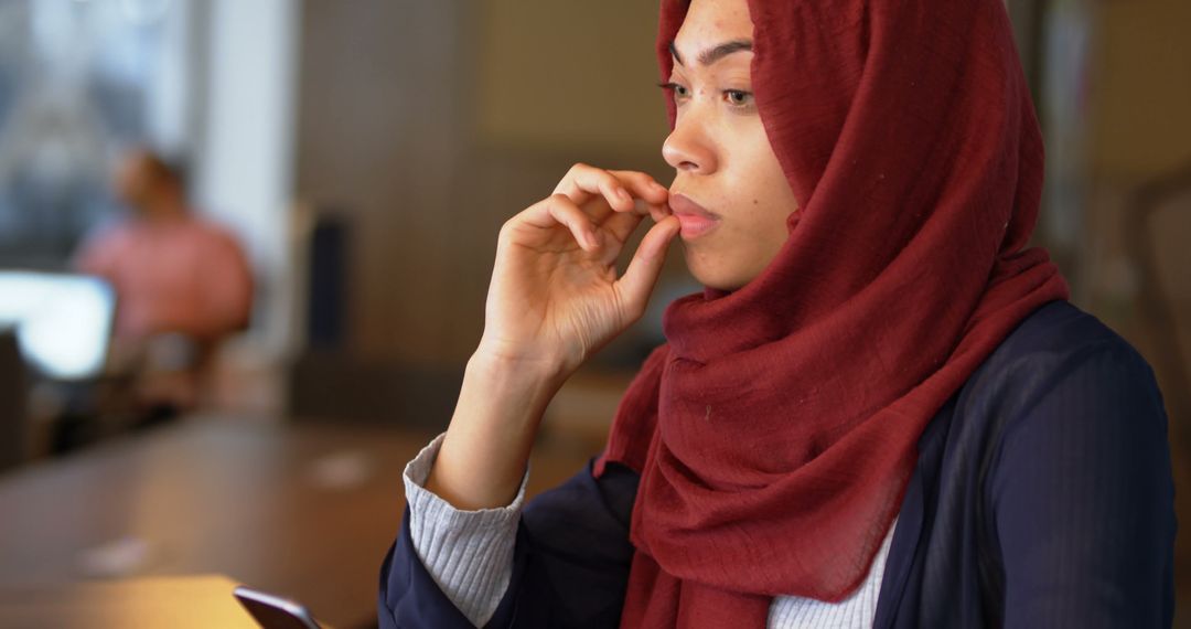 Muslim Woman Focusing with Red Hijab In Modern Workspace - Free Images, Stock Photos and Pictures on Pikwizard.com