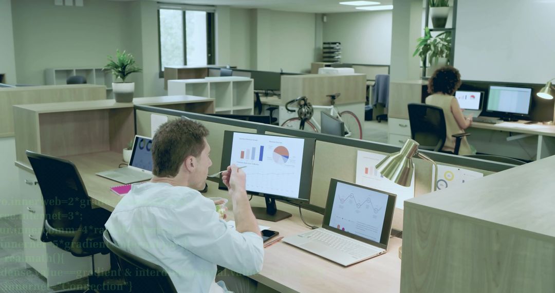 Businessman Eating Lunch While Analyzing Data on Multiple Monitors