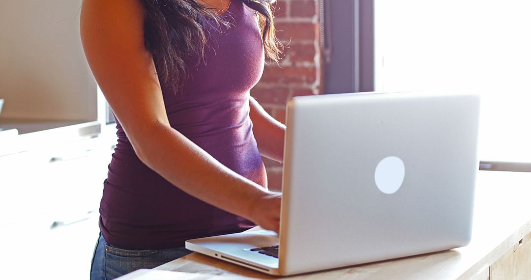 Young Woman Standing at Desk Using Laptop in Modern Workspace - Free Images, Stock Photos and Pictures on Pikwizard.com