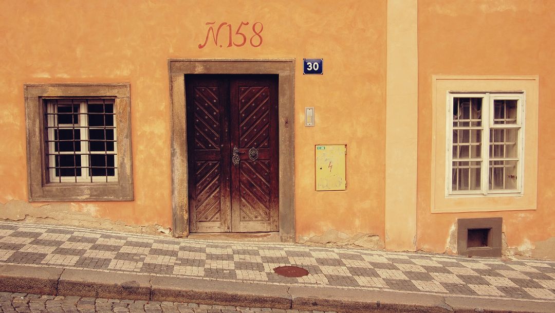 Featuring Rustic Orange Facade Featuring Ornate Wooden Door and Patterned Cobblestone Sidewalk