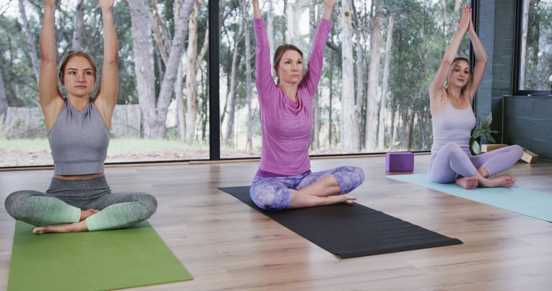 Three Women Practicing Yoga in Modern Studio with Large Windows - Free Images, Stock Photos and Pictures on Pikwizard.com