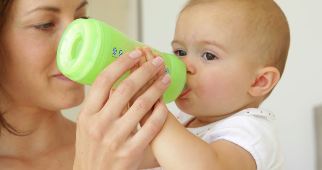 Mother Feeding Infant with Green Bottle - Free Images, Stock Photos and Pictures on Pikwizard.com