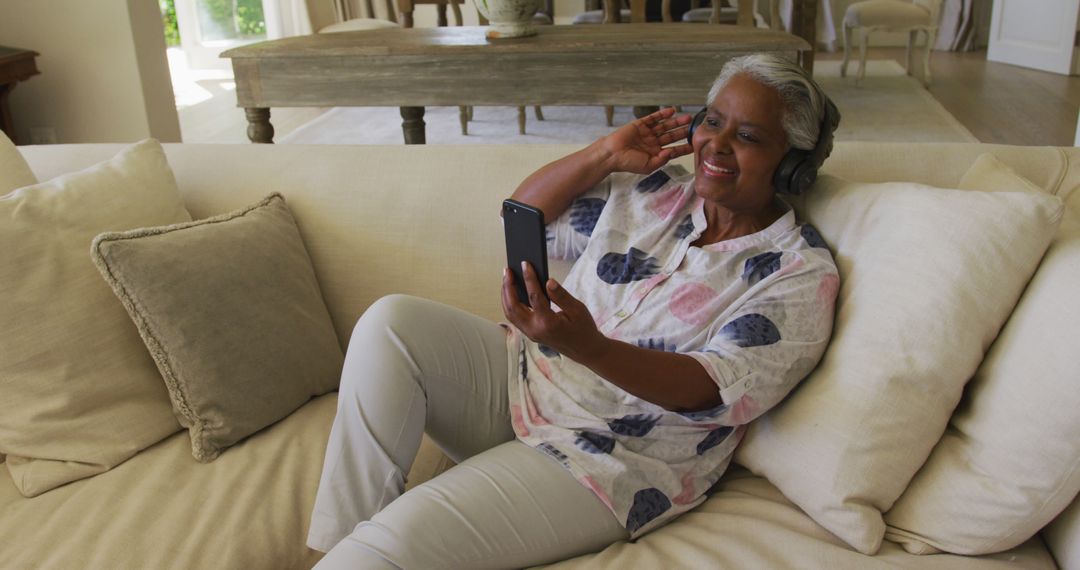 Senior Woman Enjoying Video Call at Home with Headphones and Smartphone - Free Images, Stock Photos and Pictures on Pikwizard.com