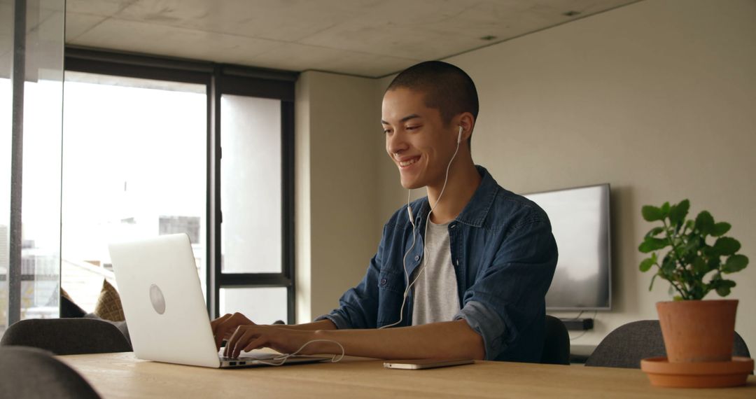 Young Man Smiling While Working on Laptop at Home - Free Images, Stock Photos and Pictures on Pikwizard.com